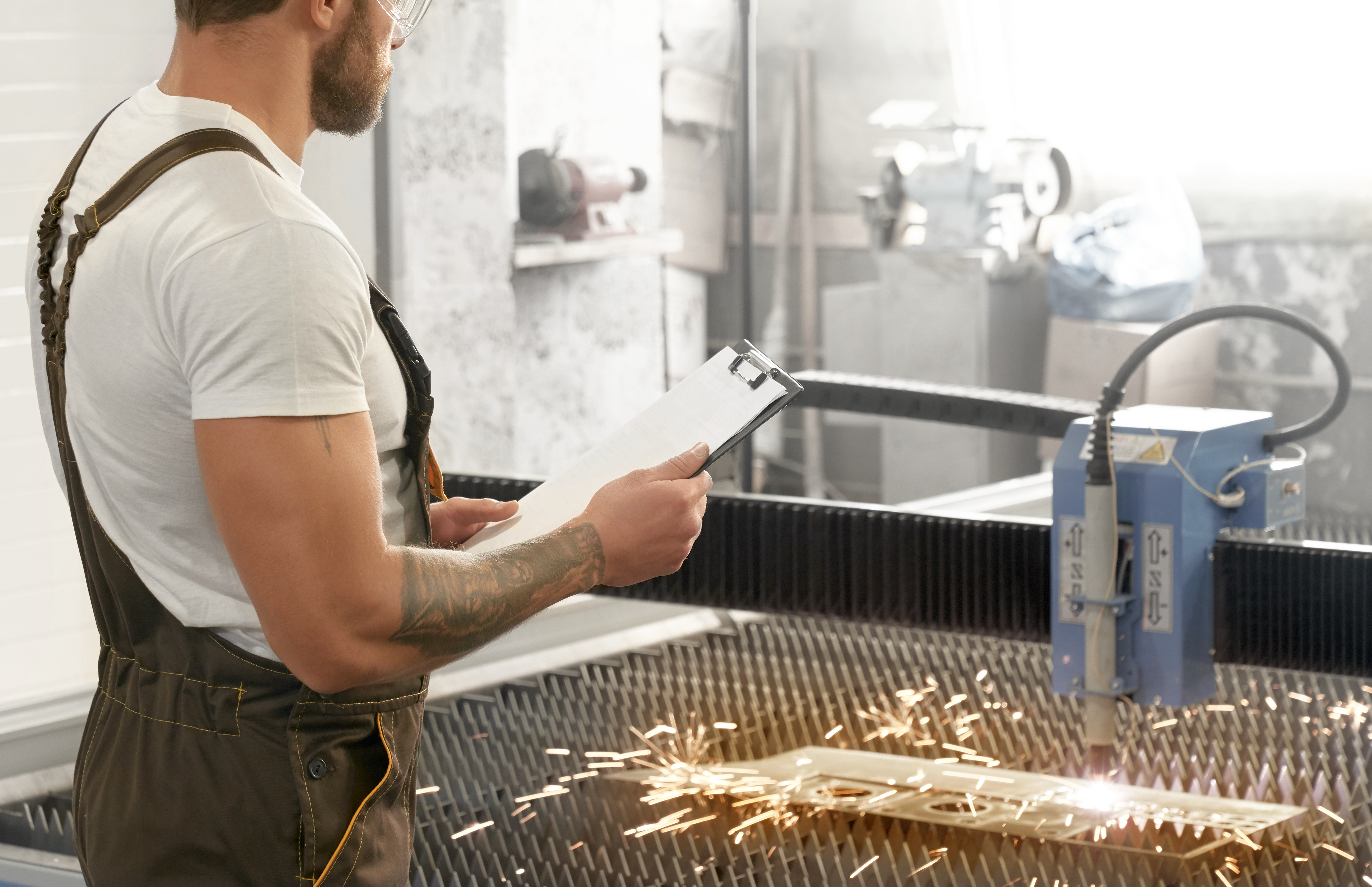 ouvrier qui surveille la machine de decoupe metal