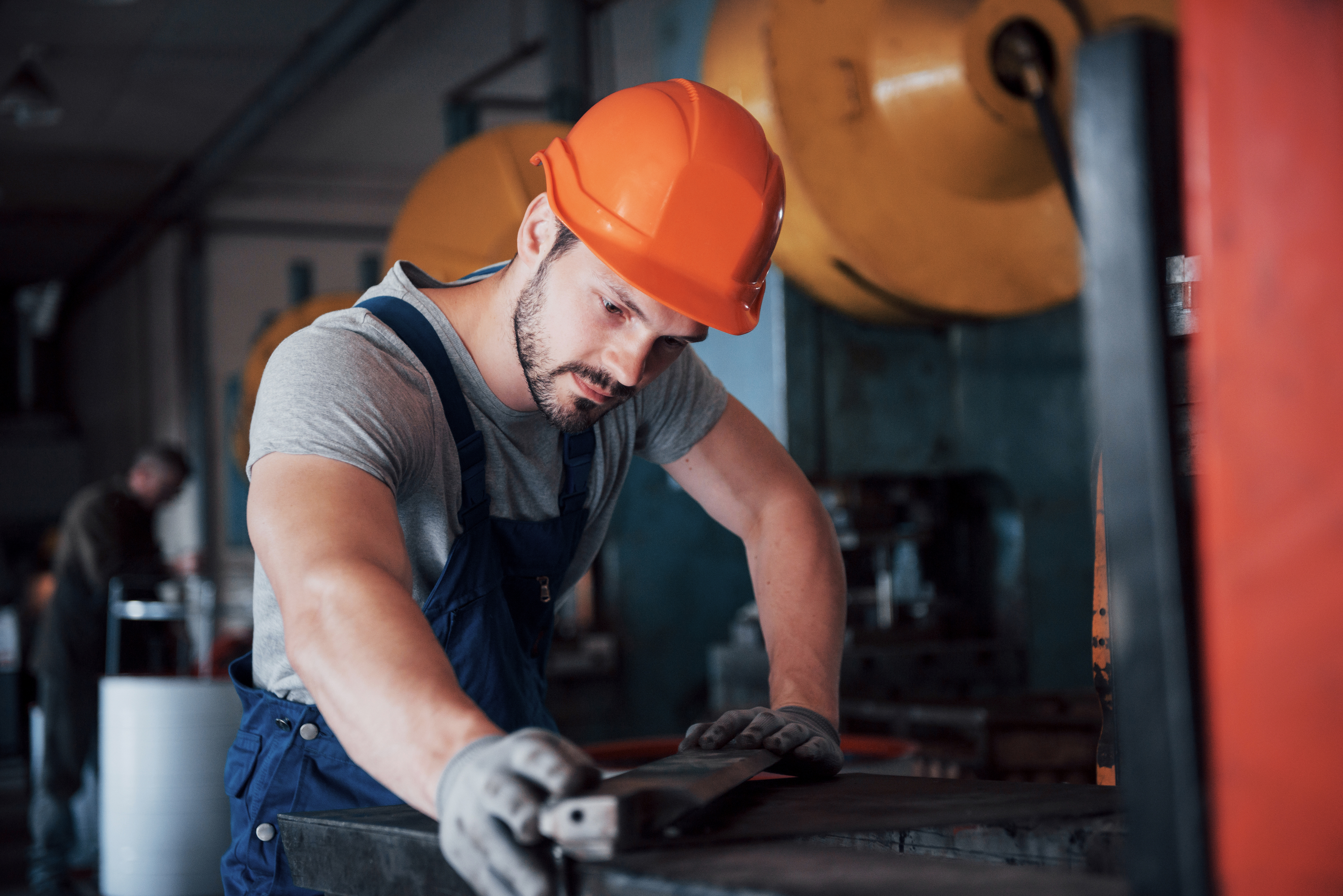 Ouvrier dans un atelier de metal qui s'occupe d'une piece 